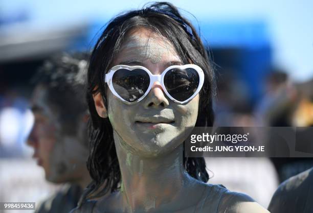 Woman is covered with mud on her face during the 21th Boryeong Mud Festival at Daecheon beach in Boryeong on July 14, 2018. - The annual festival,...