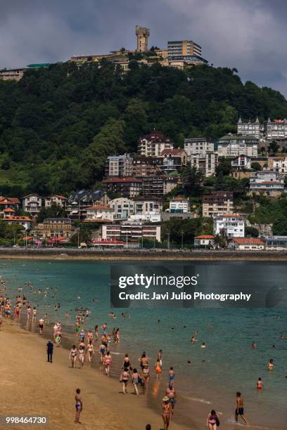 people walking along the shore of the beach on a summer day in the city of san sebastian, on the beach of ondarreta - ondarreta fotografías e imágenes de stock