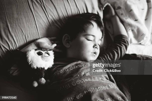 boy sleeping in his bed with stuffed animal - animal body part stock-fotos und bilder