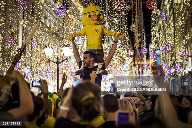 Brazilian football fans hold a yellow chick dummy wearing the number 10 jersey as they party along with tourists and revellers near the Russia 2018...