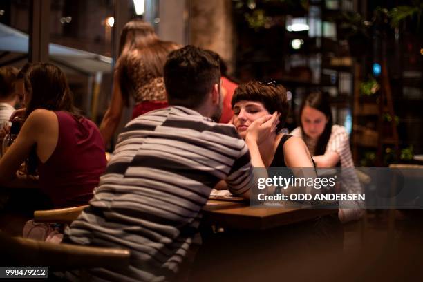 Couple share a tender moment in a cafe near the Russia 2018 FIFA football World Cup fan zone on Moscow's Red Square on July 13, 2018.