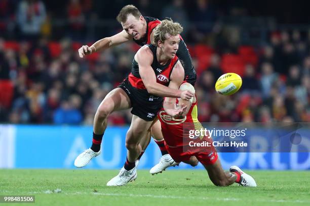 Darcy Parish of the Bombers handballs while tackled during the round 17 AFL match between the Gold Coast Suns and the Essendon Bombers at Metricon...