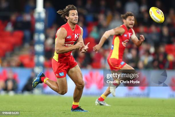 Lachie Weller of the Suns handballs during the round 17 AFL match between the Gold Coast Suns and the Essendon Bombers at Metricon Stadium on July...