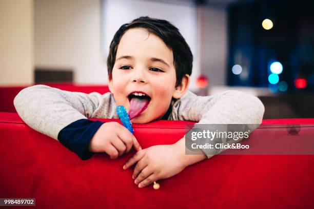 cute boy sticking his tongue out eating a lollipop (indoors) - click&boo stock pictures, royalty-free photos & images