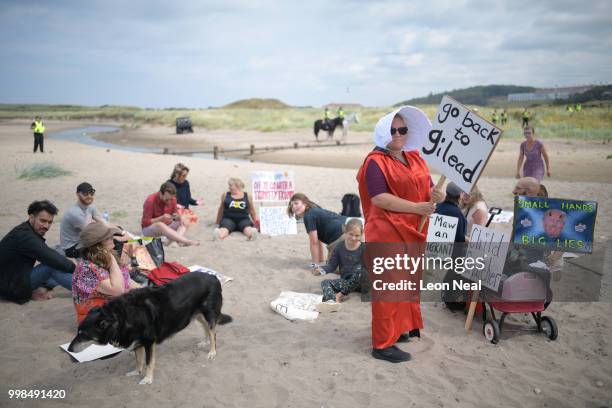 Woman wears a costume in the style of the 'Handmaid's Tale' on the beach as police patrol the area near Trump Turnberry Luxury Collection Resort...