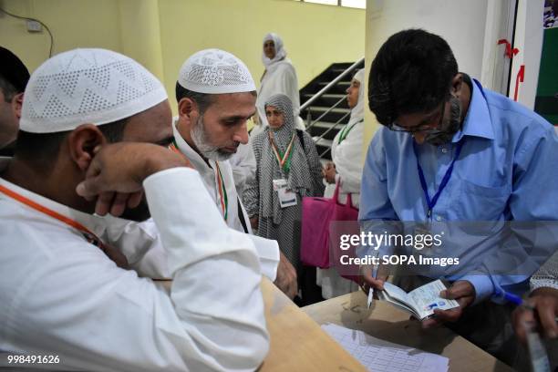 An official member of hajj house checks travel documents of Kashmiri Muslims before their departure for the annual Hajj pilgrimage in Srinagar,...