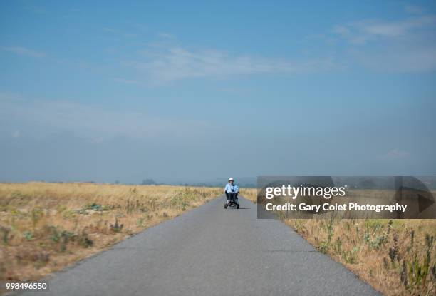 motorised wheelchair on path - gary colet stock pictures, royalty-free photos & images