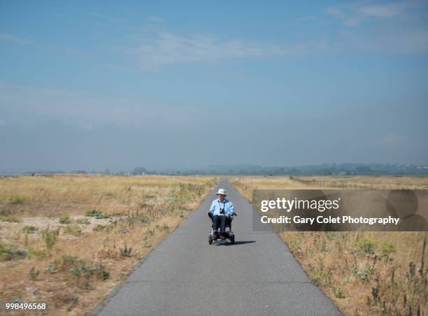 motorised wheelchair on path - gary colet stock pictures, royalty-free photos & images