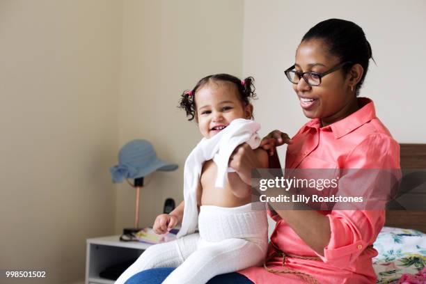 mother helping a happy child get dressed - lilly roadstones stock pictures, royalty-free photos & images