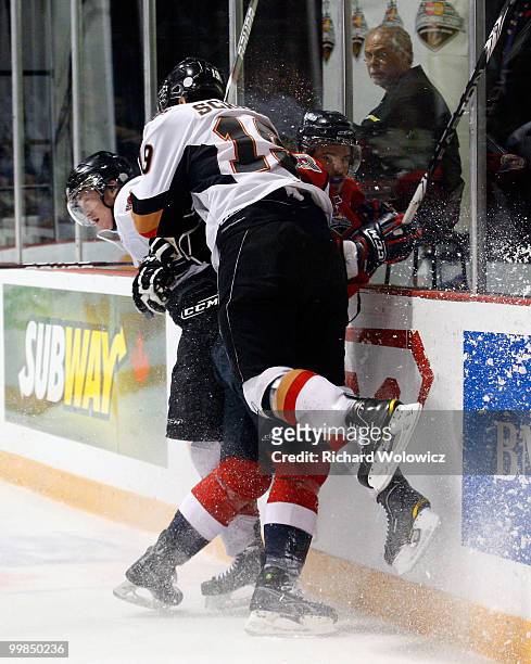 Cody Sylvester and Ian Schultz of the Calgary Hitmen body check Marc Cantin of the Windsor Spitfires during the 2010 Mastercard Memorial Cup...