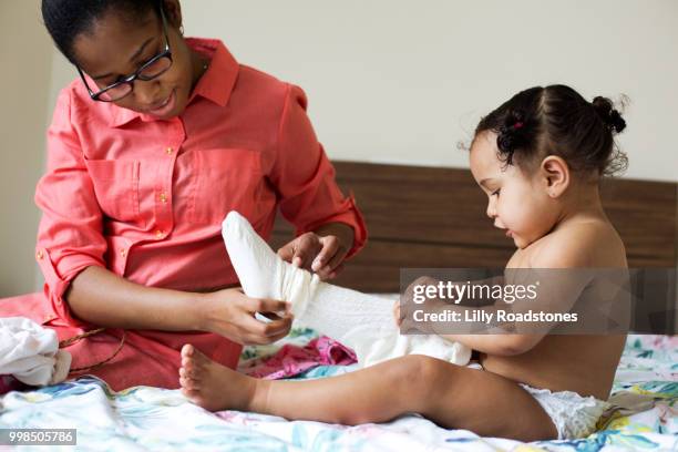 mother helping young daughter get dressed - women wearing nylons photos et images de collection