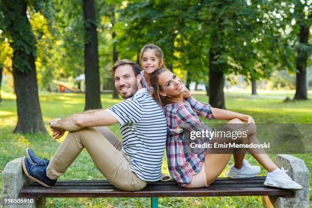 smiling young family enjoying time together in the park - emir memedovski stock pictures, royalty-free photos & images