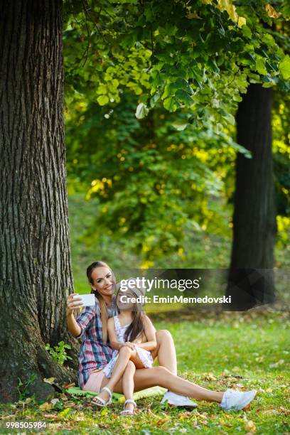 mother and daughter taking selfie in the park - emir memedovski stock pictures, royalty-free photos & images