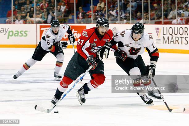 Eric Wellwood of the Windsor Spitfires skates with the puck while being defended by Zak Stebner of the Calgary Hitmen during the 2010 Mastercard...
