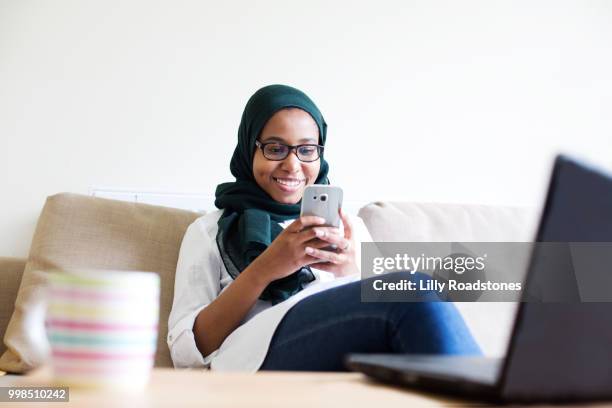 young muslim woman using mobile phone and laptop - lilly roadstones stock pictures, royalty-free photos & images