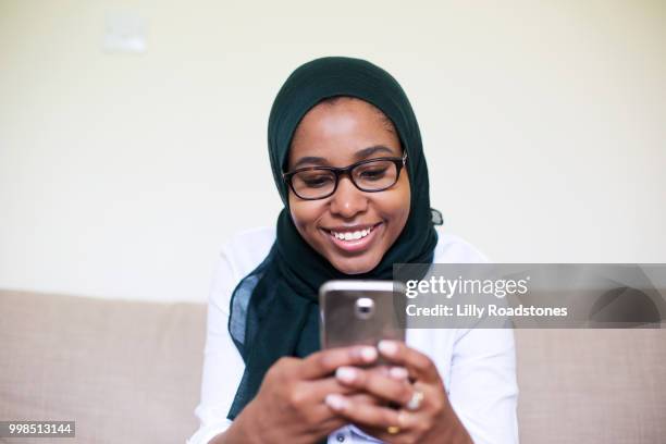 young muslim woman using mobile phone - lilly roadstones stock pictures, royalty-free photos & images