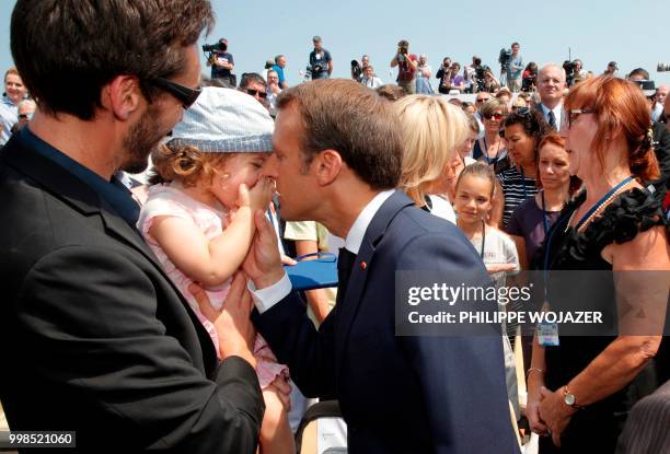 French President Emmanuel Macron kisses a child as he talks to the family of late French Gendarme Lieutenant-Colonel Arnaud Beltrame, after the...