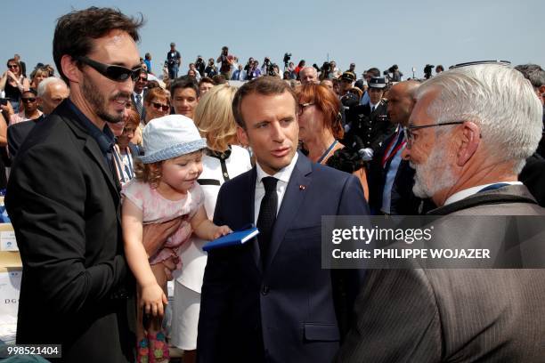 French President Emmanuel Macron talks to the family of late French Gendarme Lieutenant-Colonel Arnaud Beltrame, after the annual Bastille Day...