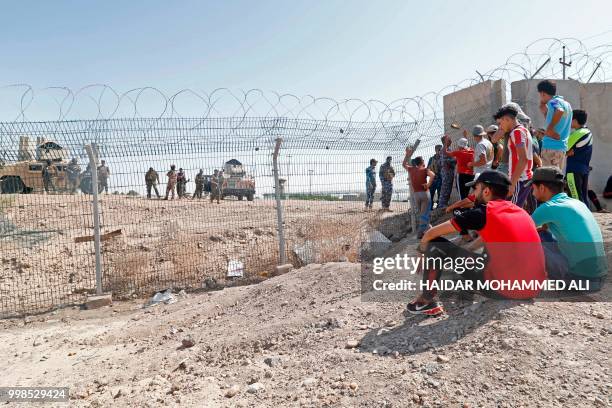 Iraqi protesters sit outside the oil fields in al-Qurnah, some 100 kilometers north of Basra, southern Iraq, as they demonstrate against unemployment...