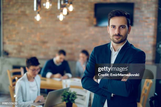 portrait of a young  businessman with arms crossed - emir memedovski stock pictures, royalty-free photos & images