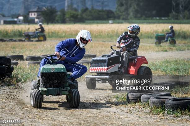Team members ride lawn-mowers as they take part in the 5th edition of the motorised lawn mower race on July 14, 2018 in Dorenaz, western Switzerland....