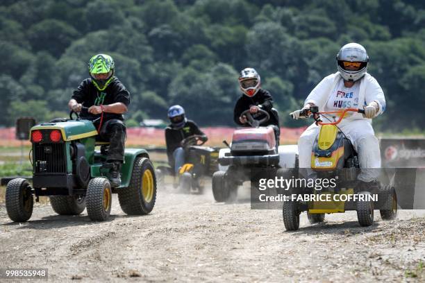 Team members ride their lawn-mowers as they take part in the 5th edition of the motorised lawn mower race on July 14, 2018 in Dorenaz, western...