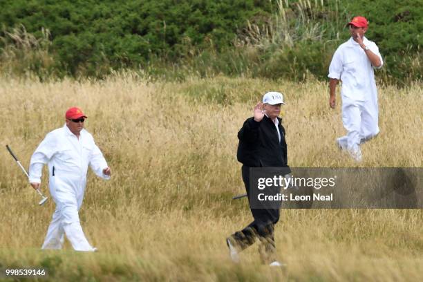 President Donald Trump waves while playing golf at Trump Turnberry Luxury Collection Resort during the President's first official visit to the United...