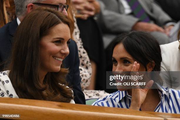 Britain's Catherine, Duchess of Cambridge, and Britain's Meghan, Duchess of Sussex react as they sit in the Royal box on Centre Court to watch...