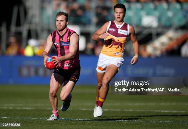 Tom Mitchell of the Hawks in action ahead of Cameron Rayner of the Lions during the 2018 AFL round 17 match between the Hawthorn Hawks and the...