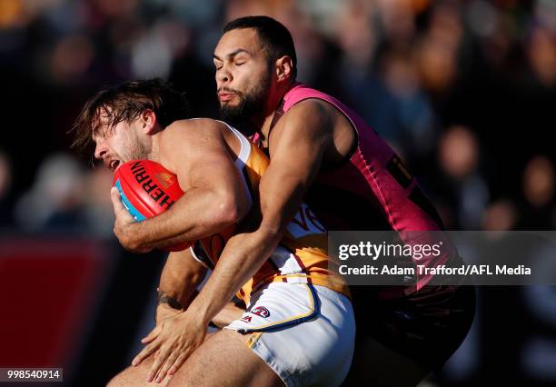 Rhys Mathieson of the Lions is tackled by Jarman Impey of the Hawks during the 2018 AFL round 17 match between the Hawthorn Hawks and the Brisbane...