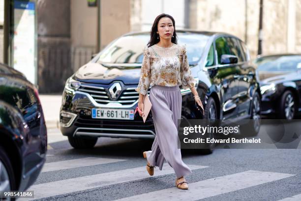 Guest wears a flower print lace mesh top, pale purple flared pants , outside Acne Studios, during Paris Fashion Week - Womenswear Fall Winter 2019,...