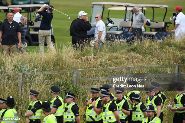 Police secure the area as U.S. President Donald Trump, wearing a hat with Trump and USA displayed on it, waits for his son Eric Trump to take his...