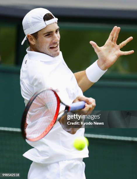 John Isner of the United States hits a forehand against Kevin Anderson of South Africa during a Wimbledon semifinal match in London on July 13, 2018....