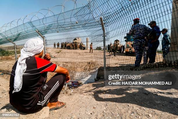 Iraqi protesters sit outside the oil fields in al-Qurnah, some 100 kilometers north of Basra, southern Iraq, as they demonstrate against unemployment...