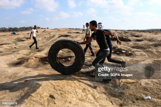 Two Palestinian youths seen clutching tires. Clashes between Palestinian citizens and the Israeli forces on the borders of the Gaza Strip east of...
