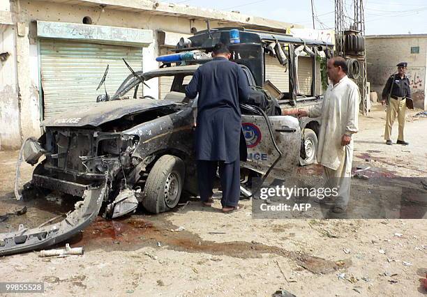 Pakistani policemen examine the wreckage of a police vehicle following a bomb attack in Dera Ismail Khan on May 18, 2010. A bomb attack targeting...