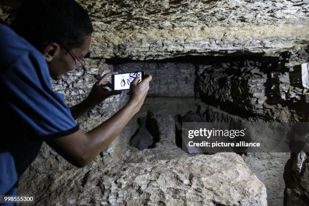 Man takes a picture of two mummies, inside a burial chamber, that was discovered by a German-Egyptian mission, at the Saqqara burial ground in Giza,...