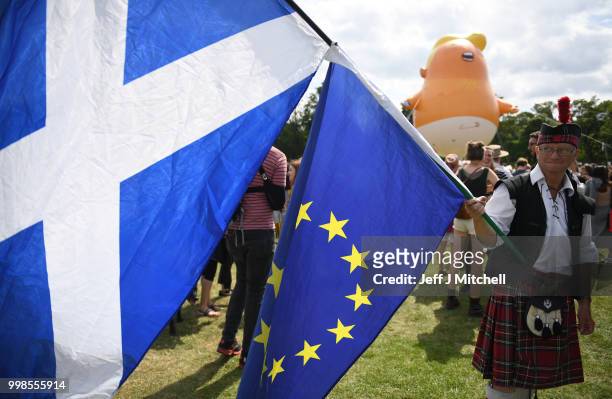 The Baby Trump Balloon floats in the distance as a man dressed in a kilt waves the Scottish Flag and the flag of the European Union while the U.S....