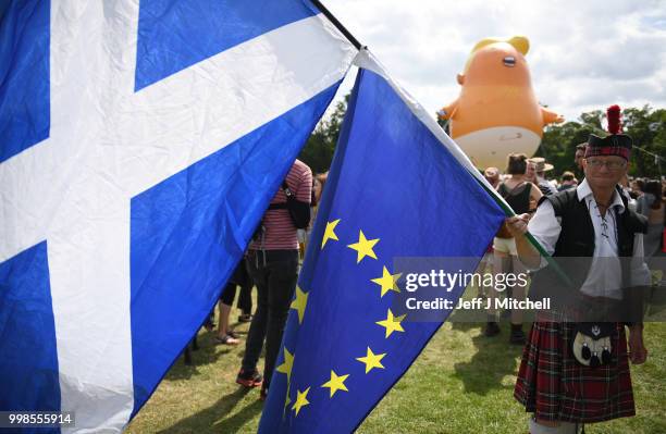 The Baby Trump Balloon floats in the distance as a man dressed in a kilt waves the Scottish Flag and the flag of the European Union while the U.S....