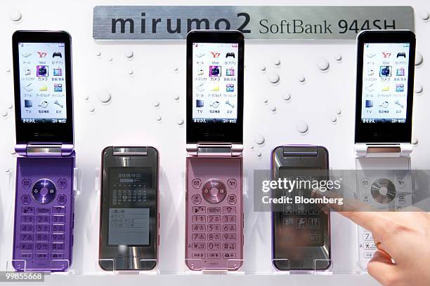 An employee touches SoftBank Corp.'s new mirumo2 944SH mobile phone, manufactured by Sharp Corp., during an unveiling in Tokyo, Japan, on Tuesday,...