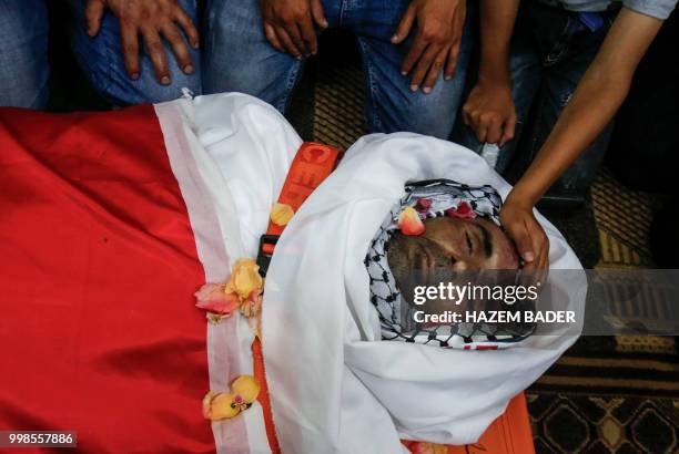 Graphic content / The son of killed Palestinian Rami Sabarneh puts his hand on his dead father's body during his funeral in the village of Beit...