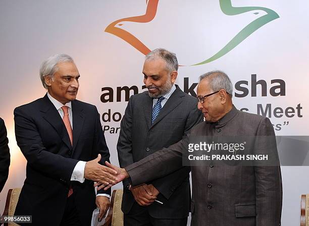 India Finance Minister Pranab Mukherjee shakes hands with Pakistan's High Commissioner to India Shahid Malik and CII President Hari S. Bhartia looks...