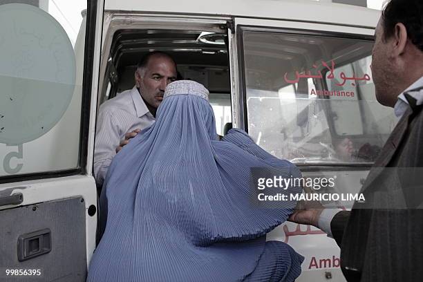 An Afghan burqa-clad woman is prevented by doctors as she attempts to get into an ambulance to accomany her wounded son while he is moved to a...