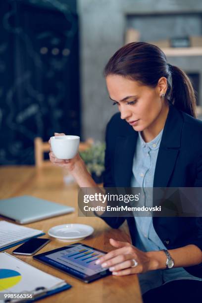 young businesswoman analyzing business report using digital tablet - emir memedovski stock pictures, royalty-free photos & images