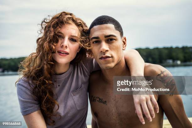 portrait of young couple sitting by lake - tatouage femme photos et images de collection
