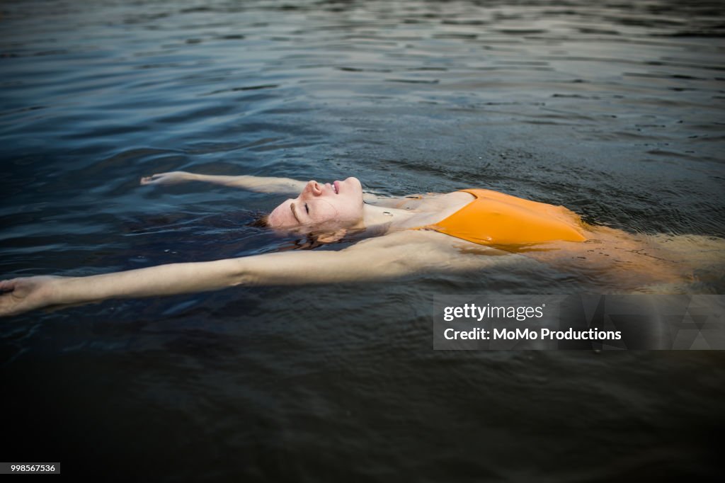 Young woman floating in the water at lake