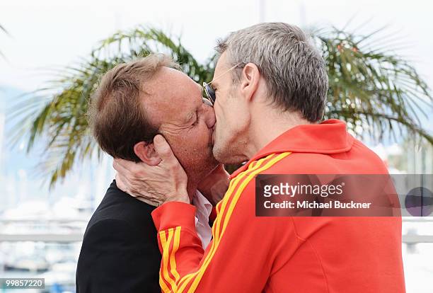 Director Xavier Beauvois receives a kiss from actor Lambert Wilson at the "Of Gods And Men" Photocall at the Palais des Festivals during the 63rd...