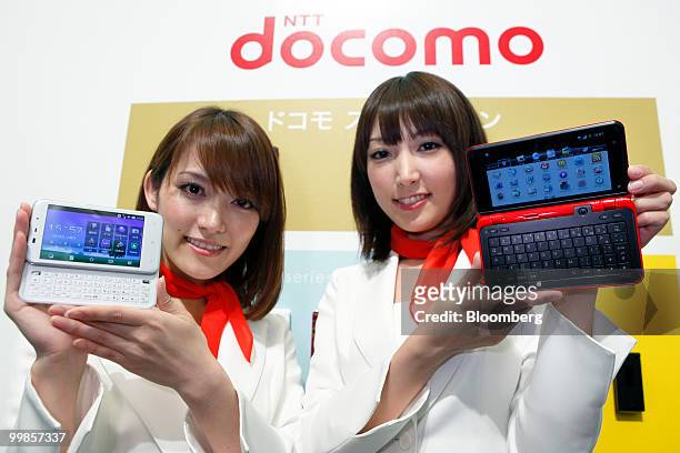 Models pose with NTT DoCoMo Inc.'s new dynapocket T-10B smartphone, left, running Microsoft Corp.'s Windows Mobile operating system, manufactured by...