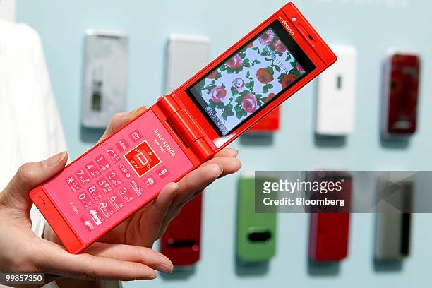 Model poses with NTT DoCoMo Inc.'s new P-05B mobile phone, made in collaboration with kate spade new york, manufactured by Panasonic Corp., during an...