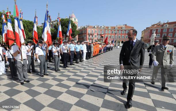 French Prime Minister Edouard Philippe reviews an honour guard of troops in Nice on July 14 during a ceremony for the second anniversary of attacks...